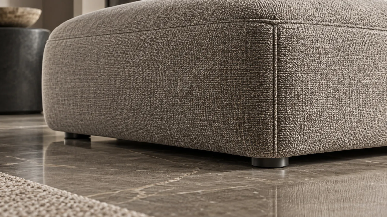 Low-angle detail of ottoman upholstery seams and floor glides