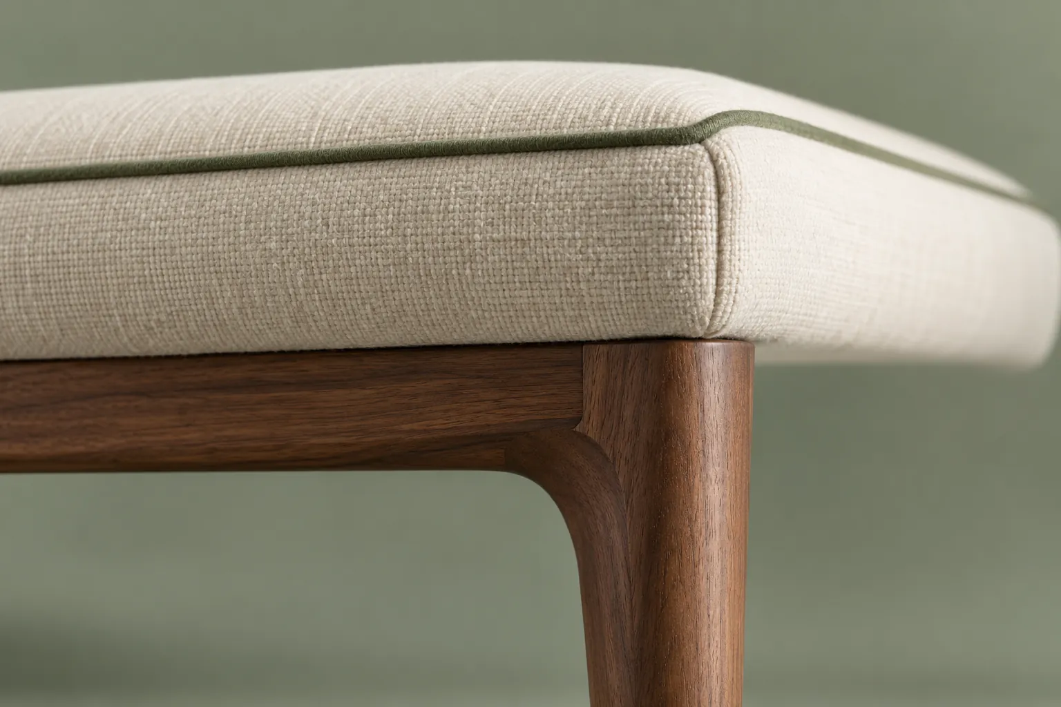Cream upholstered seat corner with green piping and a walnut joint