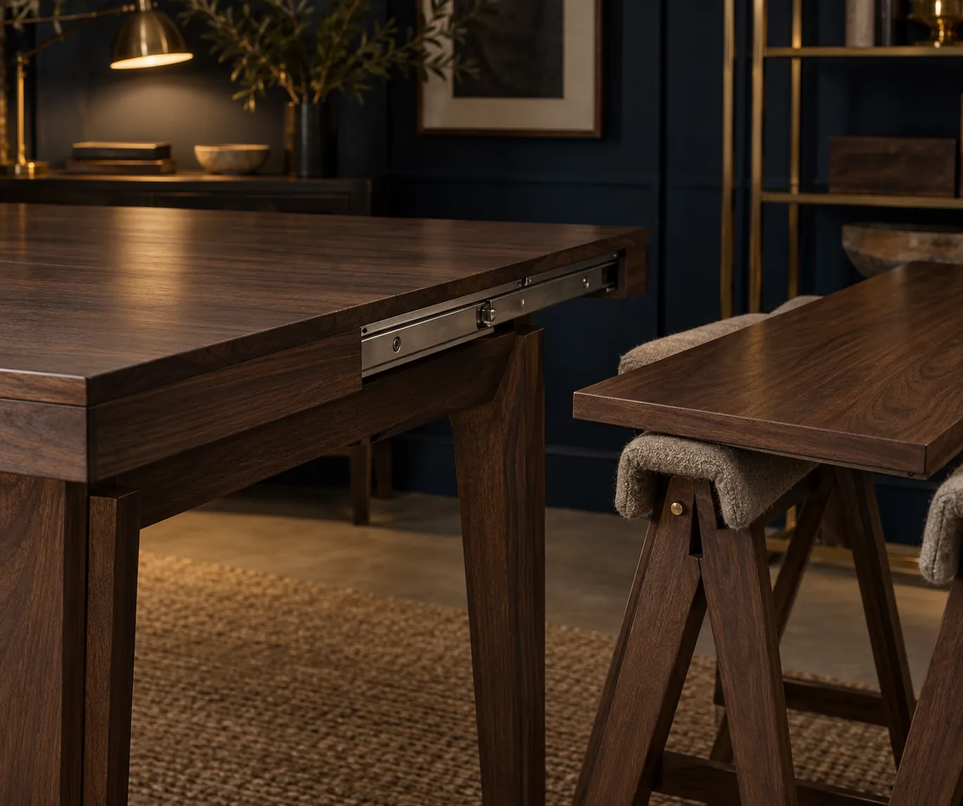 Dark wood table with extension hardware beside a separate tabletop on trestles