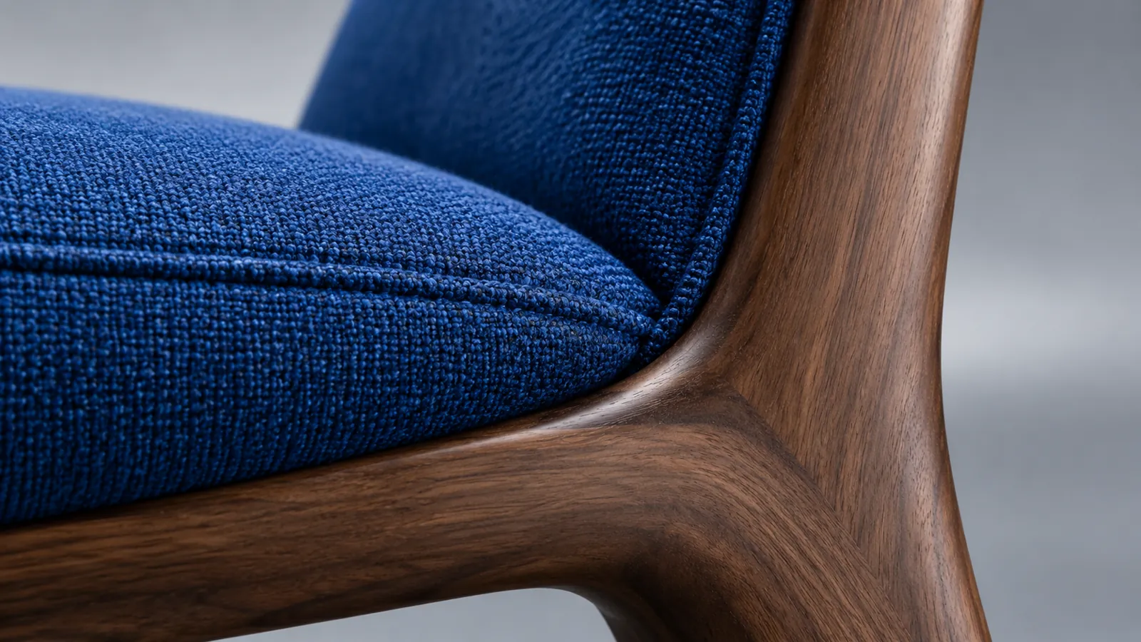 Macro view of blue upholstery seams and walnut chair frame